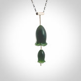 This is a very dark green flower bud pendant carved here in New Zealand by Josey Coyle. It is handmade carved jade double flower buds one placed above the other on a fine silver wire. The top is a T-shaped tube through which a silver necklace chain passes. The jade florets are handcarved from beautiful dark green New Zealand Marsden Jade and the chain is handmade from sterling silver wire.